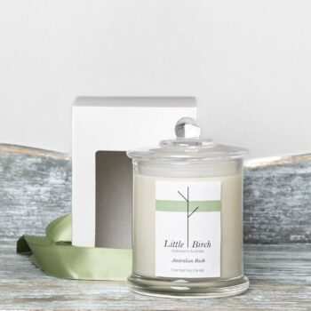 australian bush soy scented candle glass jar with lid display next to window face box and sage green ribbon for packaging