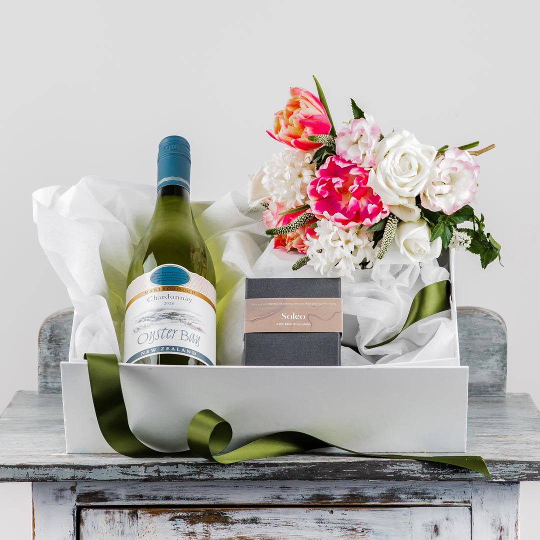 sturdy white box with magnetic lid filled with chardonnay wine bottle box of chocolates and fresh flower posy