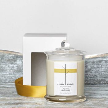 japanese and honeysuckle soy scented candle glass jar with lid display next to window face box and gold ribbon for packaging