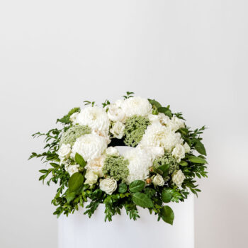 funeral circular wreath made with white and green flowers including disbud chrysanthemums roses queen anne's lace on a base of foliage