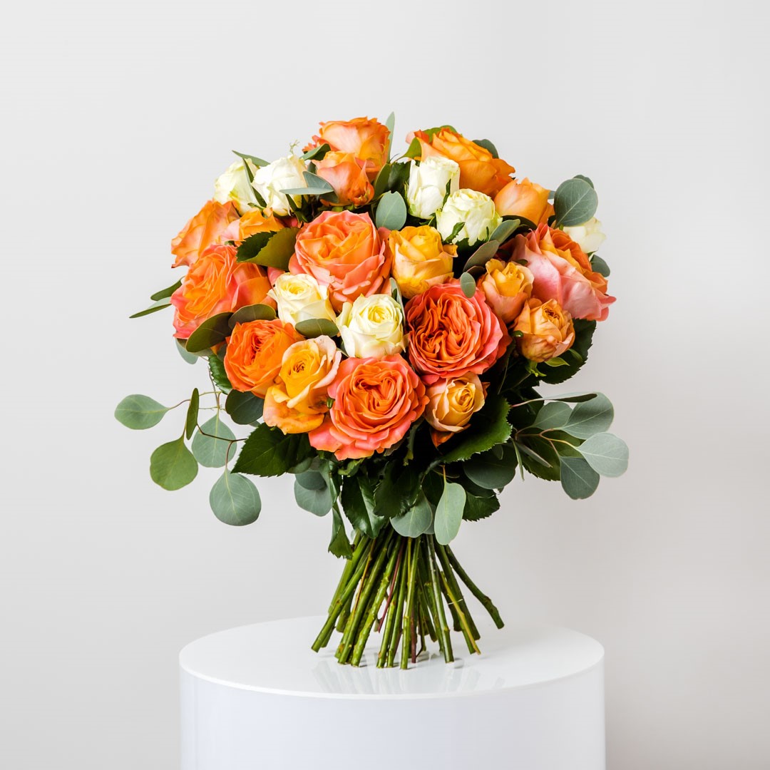a large bouquet of yellow and orange roses on a base of poly gum eucalyptus