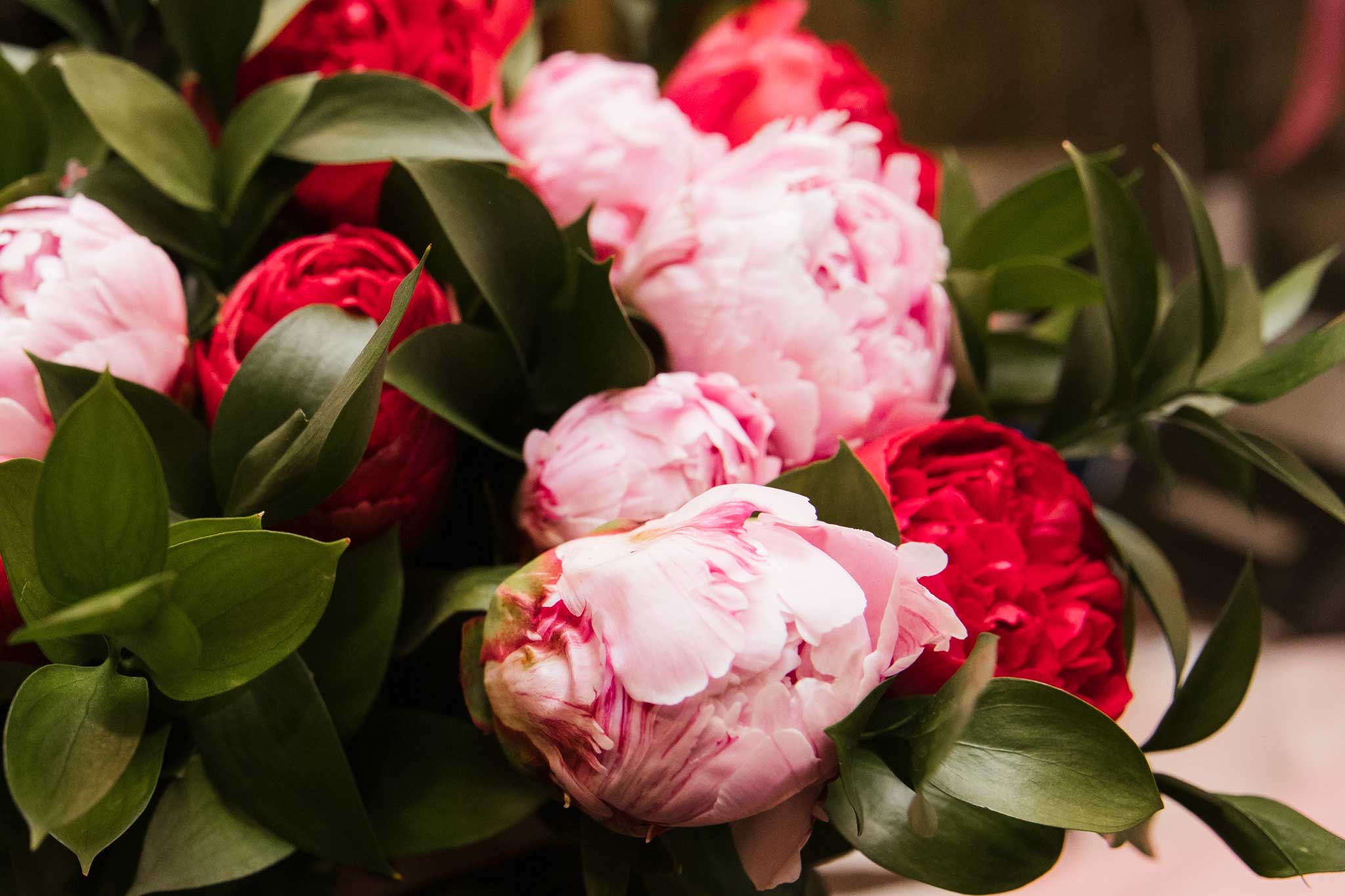 pale pink and red peony bouquet with lush green foliage