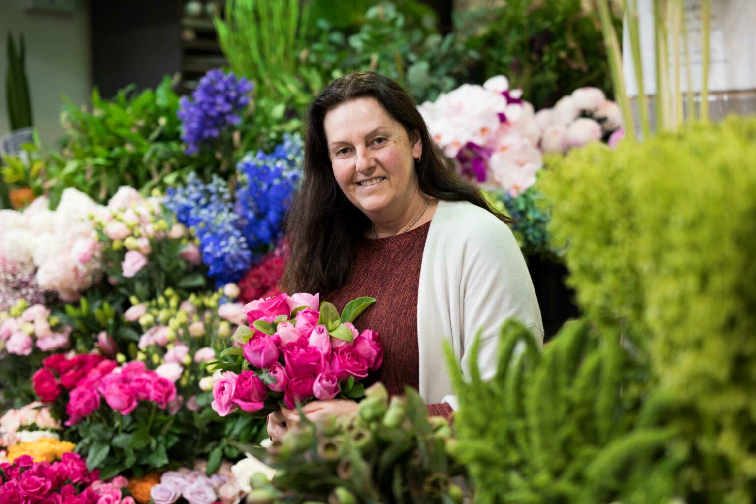 hermina holding fragrant pink roses in front of fresh flower display at camberwell florist located inside camberwell fresh food market camberwell junction