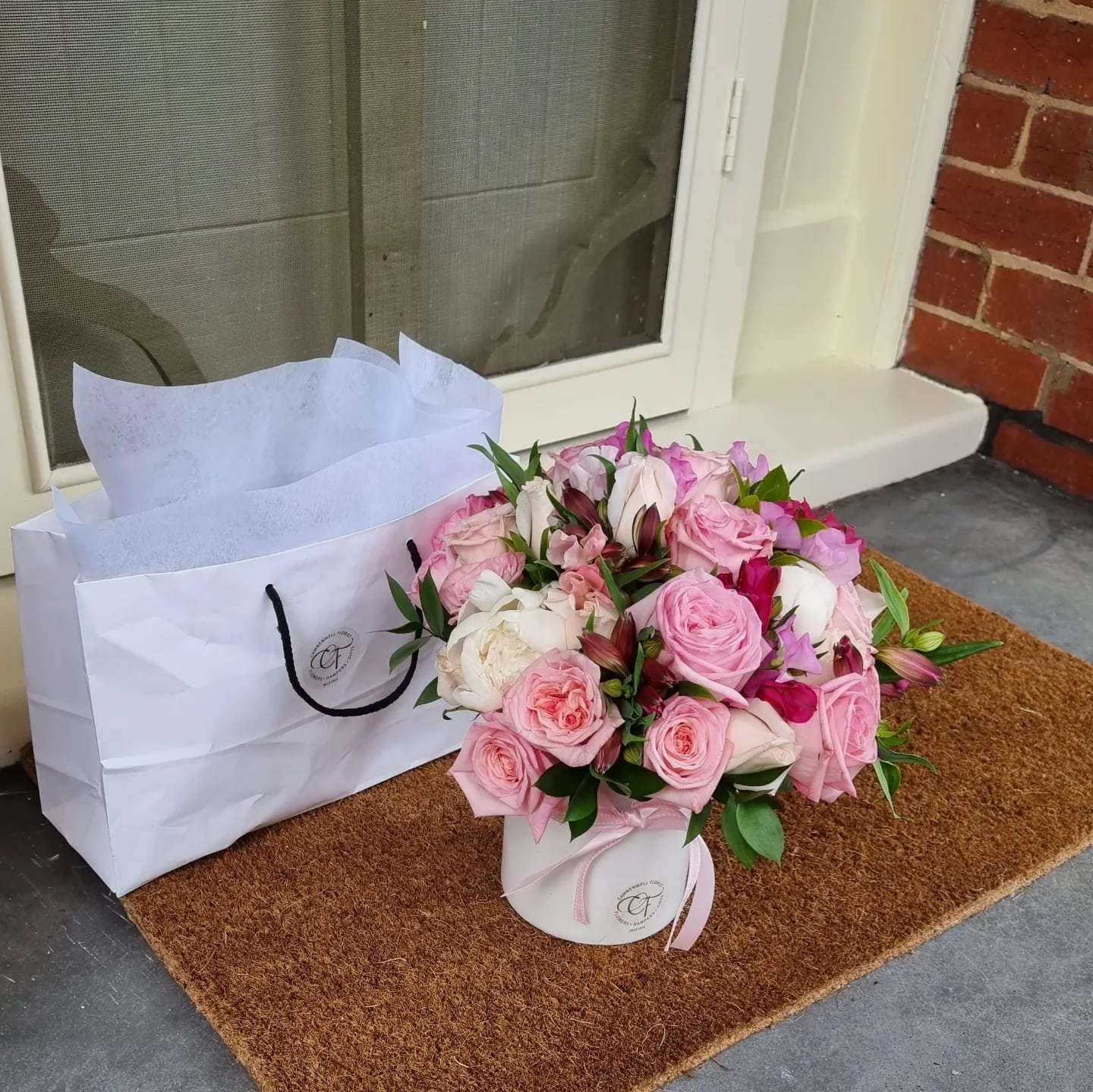 Mother's Day Flowers. Short white ceramic vase filled with pink flowers