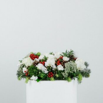 table centre piece made with fresh spruce red berries miniature pinecones and white flowers rectangle thirty centimetres long