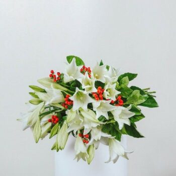 white christmas lily bouquet with red berries and foliage